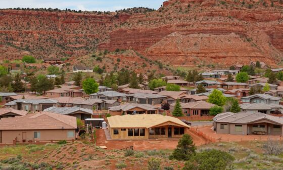 A residential neighborhood with houses and red rock formations in the background.