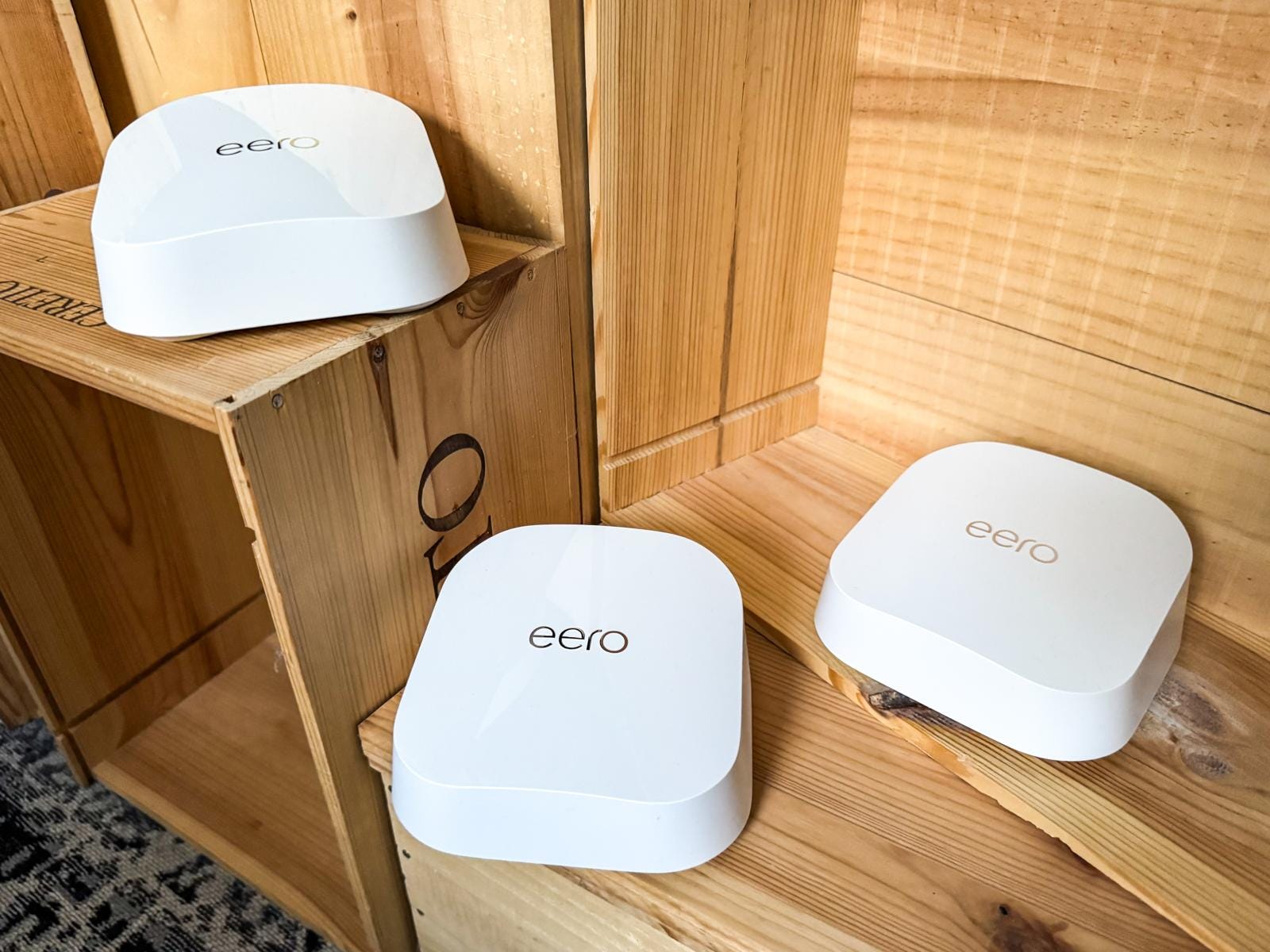 Three Eero Wi-Fi routers placed on wooden shelves.